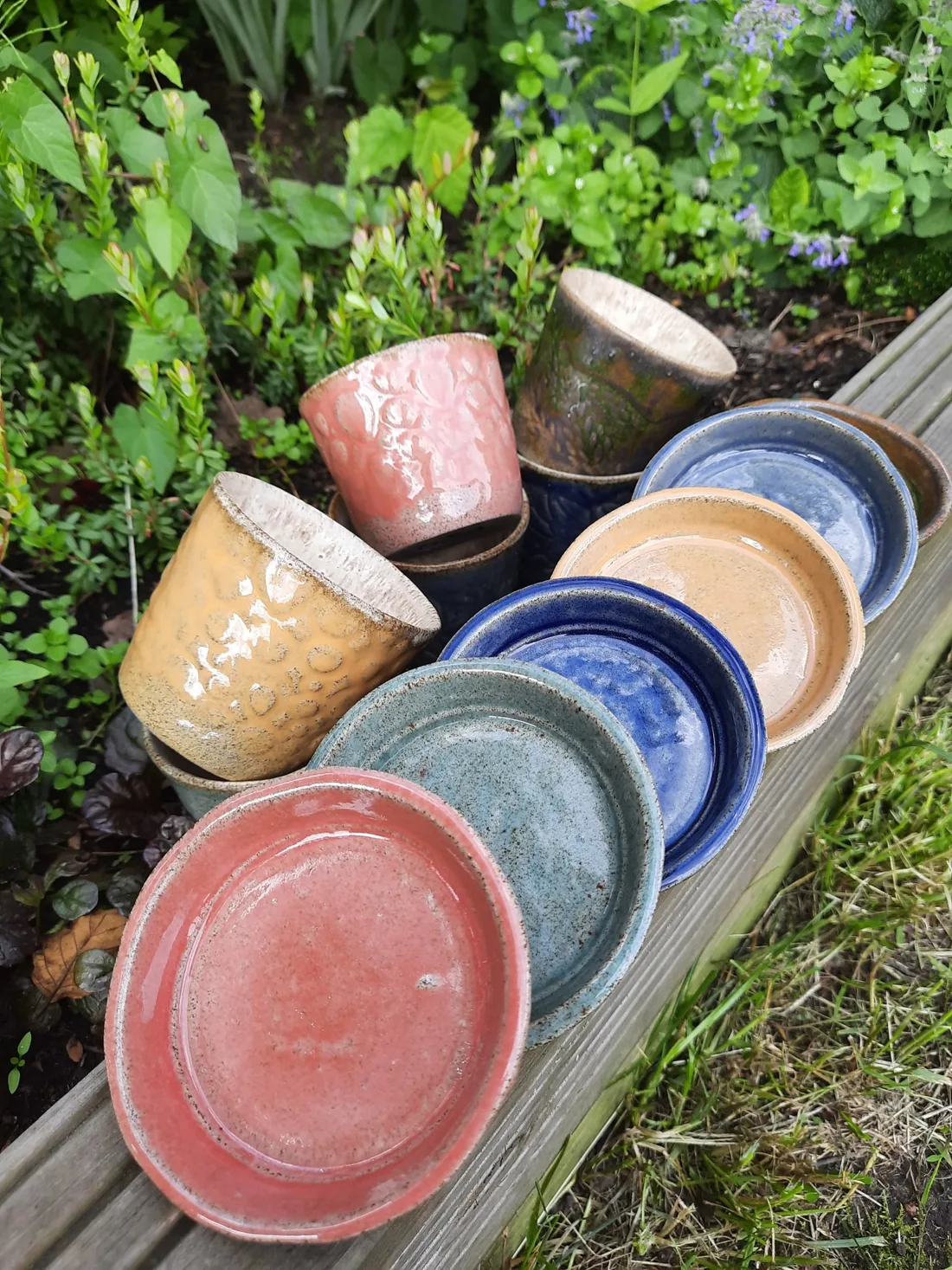 Kolorowe ceramiczne talerze, misy i kubki ułożone w ogrodzie