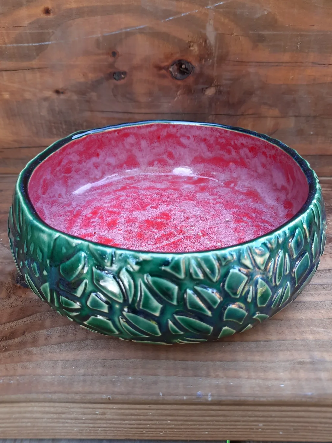 Zielono-czerwona ceramiczna misa na drewnianym blacie