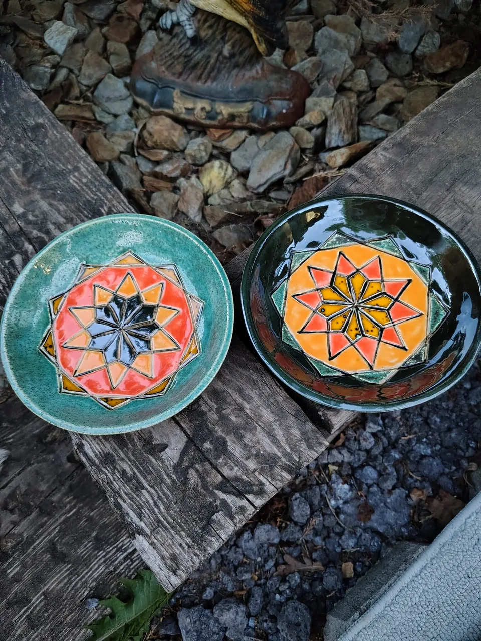 Dwa ceramiczne talerze z kwiatowymi ornamentami, turkusowy i ciemnozielony, na drewnianej powierzchni